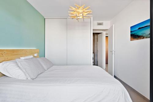 - une chambre avec un lit blanc et un lustre dans l'établissement Porticcio - T2 neuf à 5min à pieds de la plage, à Porticcio