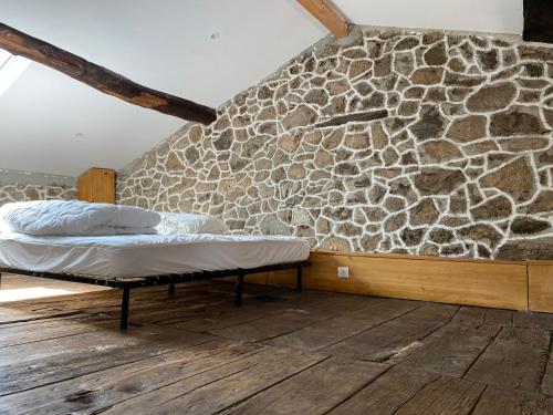 Cette chambre comprend 2 lits et un mur en pierre. dans l'établissement Charmante maison de village, à Arbori