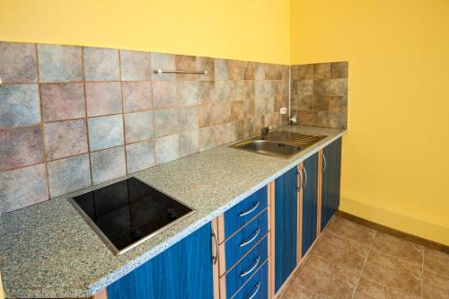 d'une cuisine avec des placards bleus, un évier et des murs jaunes. dans l'établissement Апартамент Слънчев Ден, à Balchik