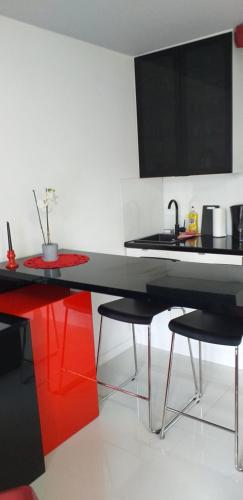 a kitchen with a black and red counter and chairs at Apartamenty Centrum Rynek Mała Dwójka in Kielce