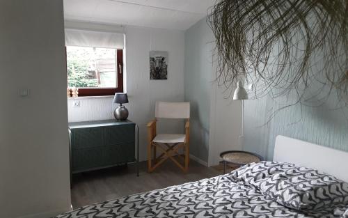 ein Schlafzimmer mit einem Bett, einem Stuhl und einem Fenster in der Unterkunft Chalet in Bad Sachsa