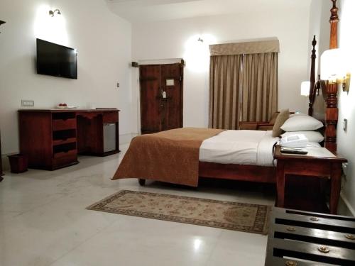 a bedroom with a bed and a desk and a television at Fateh Garh Resort by Fateh Collection in Udaipur