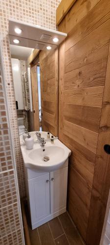 a bathroom with a white sink and a wooden wall at Studio Uissan pour 5 personnes à côté des pistes in LʼHuez