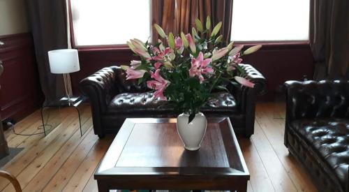 a vase of flowers on a coffee table in a living room at B&B De Gilleminus in Temse