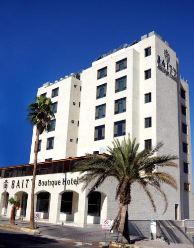 a large white building with palm trees in front of it at Baity Boutique Hotel in Aqaba