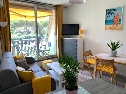 a living room with a couch and a tv at Super Appart ! Terrasse, Clim, Parking, 2min Plage. in La Grande-Motte