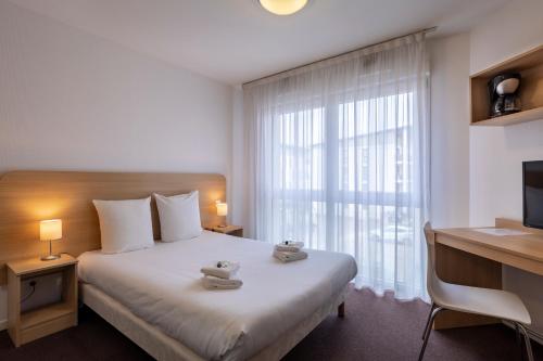 a bedroom with a bed and a desk and a window at The Originals Residence, Kosy Appart'hotels Troyes City & Park in Troyes
