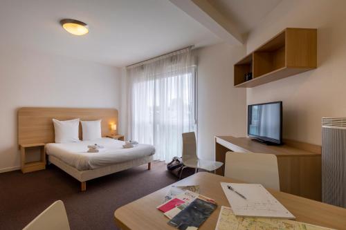 a hotel room with a bed and a television at The Originals Residence, Kosy Appart'hotels Troyes City & Park in Troyes