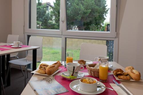a table with a breakfast of bread and orange juice at The Originals Residence, Kosy Appart'hotels Troyes City & Park in Troyes