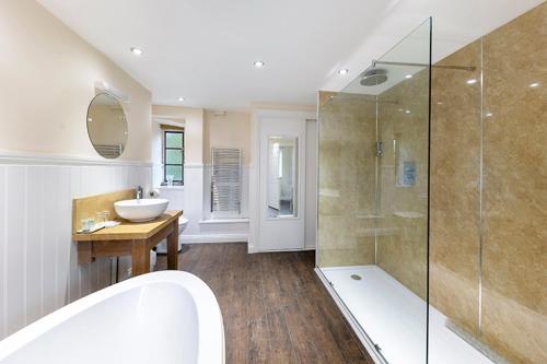 a bathroom with a tub and a sink and a shower at Haselbury Mill in Crewkerne