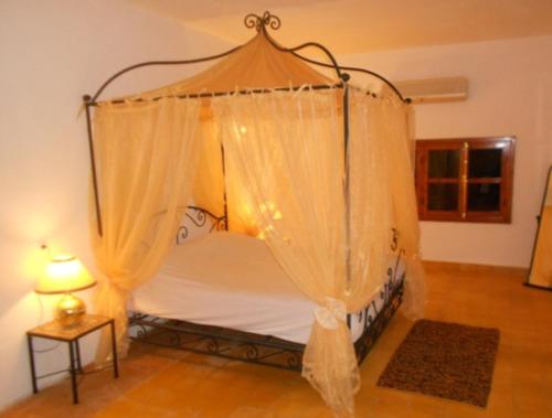 a bed with a canopy in a room with a lamp at Villa Yasmina in Douar Blidene