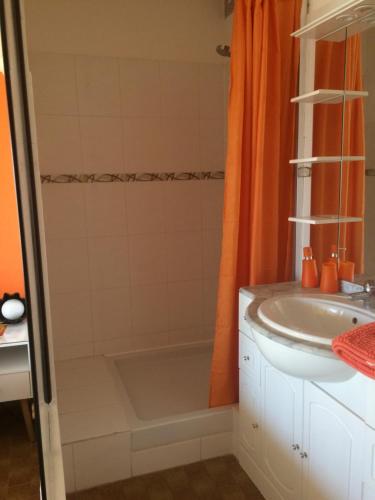 La salle de bains est pourvue d'un rideau de douche orange et d'un lavabo. dans l'établissement Studio Naturiste PaulAna Héliopolis L39, au Cap d'Agde