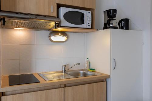 a kitchen with a sink and a microwave at The Originals Residence, Kosy Appart'hotels Troyes City & Park in Troyes