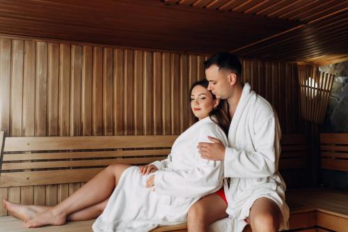 a man and woman sitting in a sauna at Hotel Podgorie Spa in Bukovel