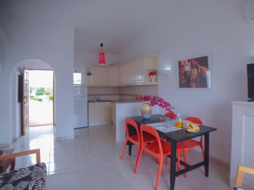 a kitchen and dining room with a table and red chairs at Typical TM Flat with a Terrace and Sea View in VSR in Porches