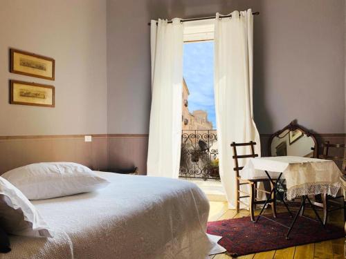 a bedroom with a bed and a table and a window at Il Salotto di Maria Pia in Syracuse