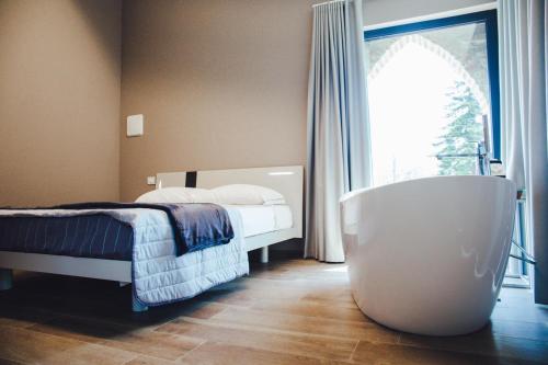 1 dormitorio con bañera, cama y ventana en L’infinito residence en Castelvetro Piacentino