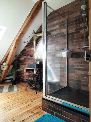 - une douche en verre dans une chambre dotée d'un mur en briques dans l'établissement Le Chic Broc Ground, à Vichy