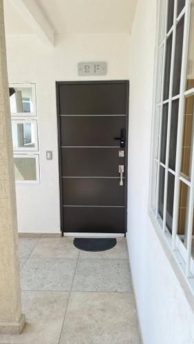 a large black door in a room with windows at Departamento en condominio con alberca y área infantil in Manzanillo