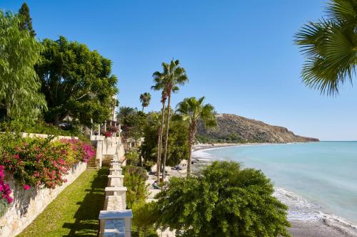 a view of a beach with palm trees and the ocean at Columbia Beach Resort in Pissouri
