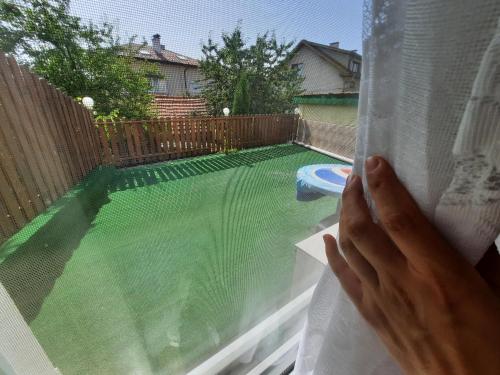 una persona mirando por una ventana a una piscina en Guest House Zodiac, en Samokov