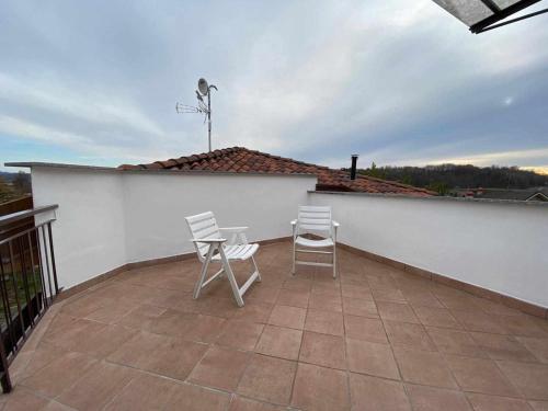 a patio with two chairs and a white wall at Casa Vacanza Amelia in Bosisio Parini
