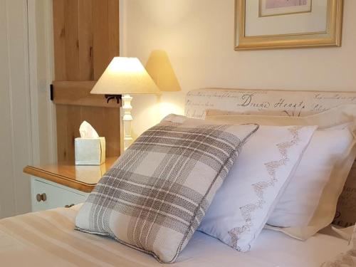 a bed with a pillow and a lamp on a table at Stone Mouse Cottage in Harrop Fold