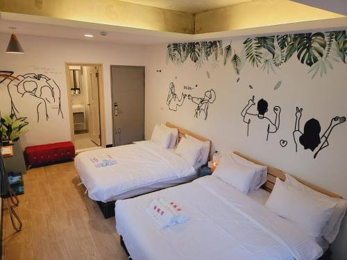 2 camas en una habitación con dibujos en la pared en Red Rose B&B漫楓宿民宿 桃園市民宿110號 en Longtan