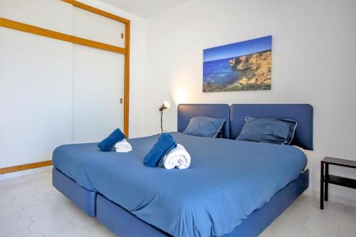 ein blaues Bett mit blauen Kissen im Schlafzimmer in der Unterkunft Sea View Apartment - 3 Swimming Pool & Fitness in Albufeira