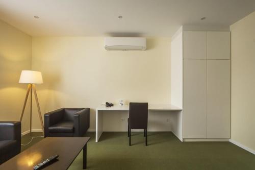 a room with a desk and two chairs and a table at Hotel Sete Cidades in Ponta Delgada