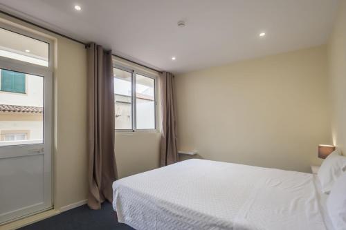 a bedroom with a white bed and a window at Hotel Sete Cidades in Ponta Delgada