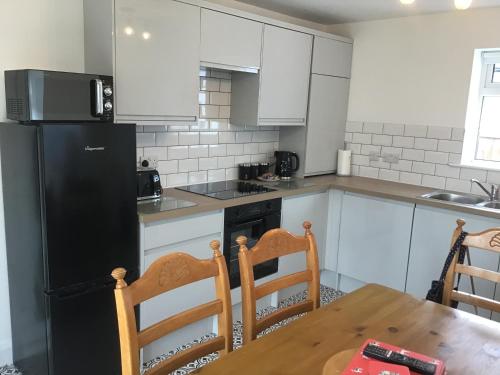 eine Küche mit einem Tisch und einem schwarzen Kühlschrank in der Unterkunft 3 bed bungalow Penrhyn Bay Llandudno in Llandrillo-yn-Rhôs