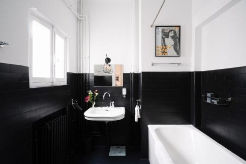 La salle de bains en noir et blanc est pourvue d'un lavabo et d'une baignoire. dans l'établissement Smartflats Design - Esplanade, à Bruxelles