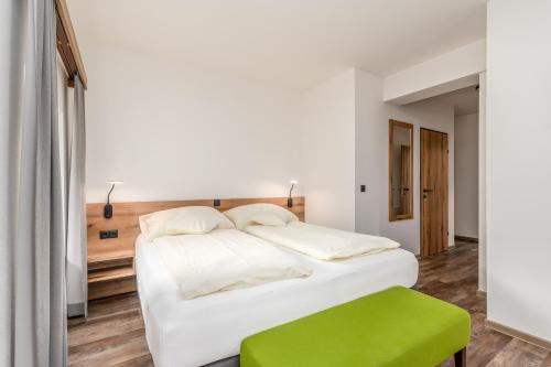 a bedroom with a white bed and a green stool at Landgasthof Bierfriedl in Pruggern