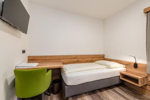 a bedroom with a bed and a desk and a green chair at Landgasthof Bierfriedl in Pruggern
