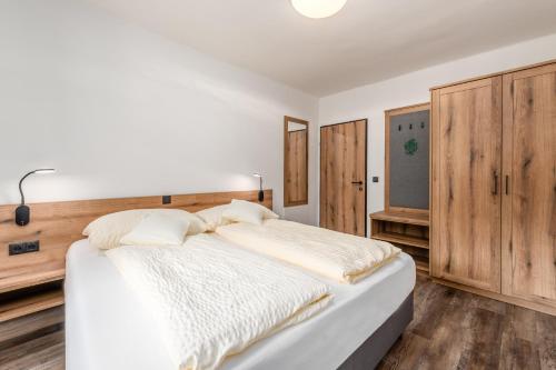 a white bed in a bedroom with wooden cabinets at Landgasthof Bierfriedl in Pruggern