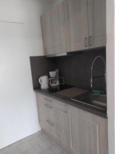 une cuisine avec des armoires blanches et un évier dans l'établissement charmant studio à Balaruc les bains, à Balaruc-les-Bains