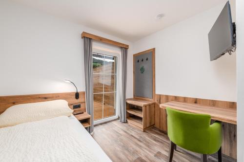 a bedroom with a bed and a desk and a green chair at Landgasthof Bierfriedl in Pruggern