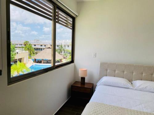 een slaapkamer met een groot raam met uitzicht op een zwembad bij Apartamento Cleo in Cancun