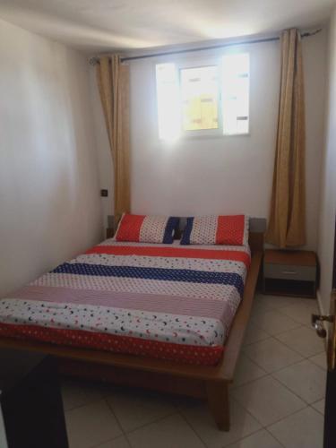 um quarto com uma cama num quarto com uma janela em bungalow de charme em El Harhoura