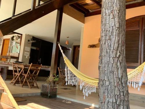 een veranda met een hangmat en een boom in een huis bij Pousada Hibiscos in Serra do Cipo