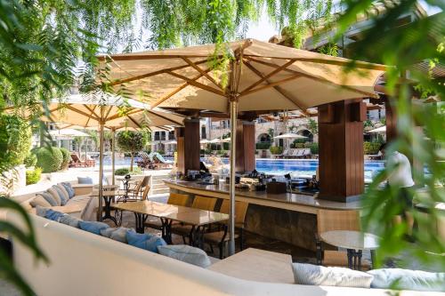 a patio with tables and umbrellas next to a pool at Columbia Beach Resort in Pissouri