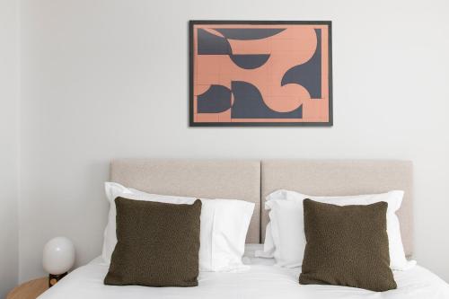 a bed with white pillows and a painting above it at Cove Minshull Street in Manchester