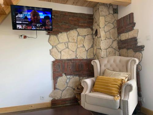 Habitación con pared de piedra, silla y TV. en Siedlisko Przyjazne Progi en Rusocice