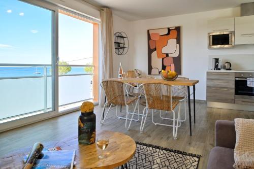 a kitchen and living room with a table and chairs at Residence Des Îles in LʼÎle-Rousse