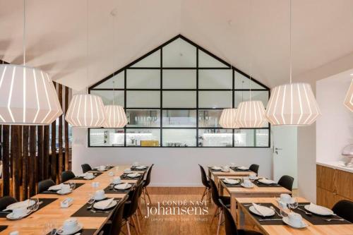 a large dining room with wooden tables and chandeliers at Sobreiras Alentejo Country Hotel in Santa Margarida da Serra