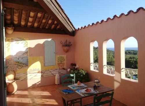 a patio in a house with a table and windows at HAMEAU DES AMANDIERS - vue mer, golf et vignes in Saint-Cyr-sur-Mer