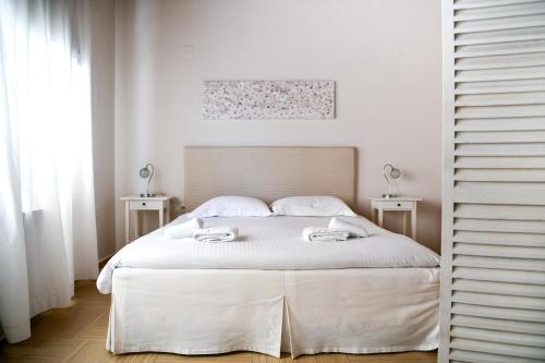 a white bedroom with a bed and two tables at Serenity Luxury Villa, Skiathos in Agia Paraskevi