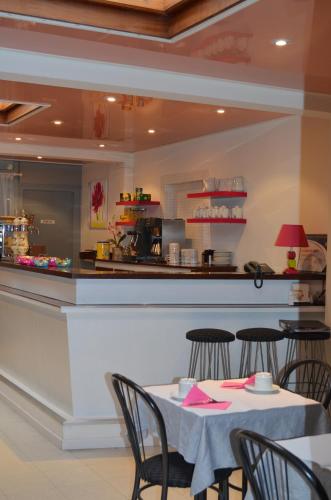 un restaurant avec une table, des chaises et un comptoir dans l'établissement Hôtel de La Croix de Malte, à Cherbourg en Cotentin