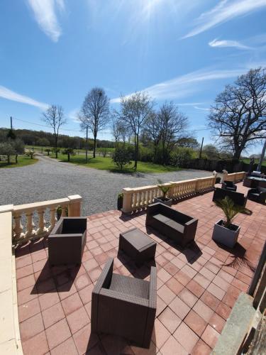 eine Terrasse mit Sofas, Tischen und einem Zaun in der Unterkunft La halte de la vilaine in Sainte-Anne-sur-Vilaine